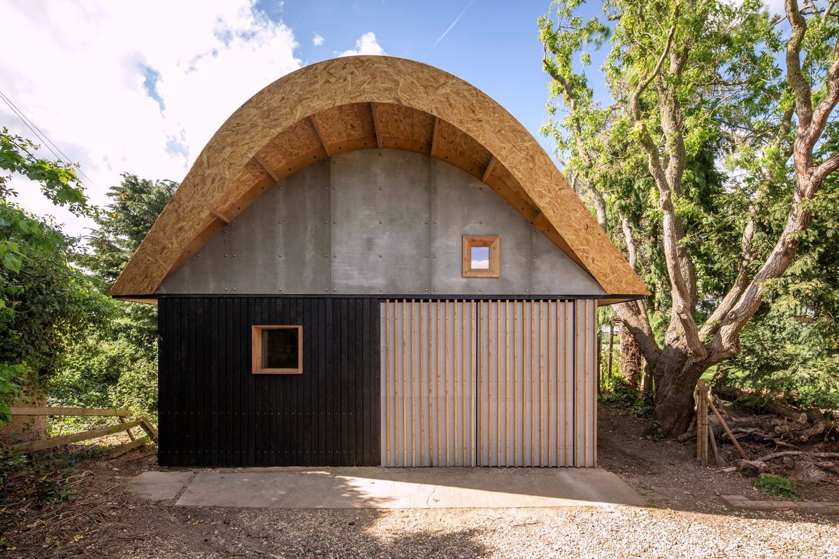 Barn-style garden room in Hertfordshire with a curved timber roof and grey and charred timber cladding
