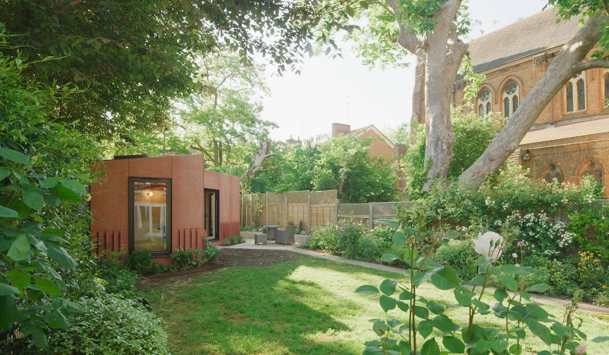 A contemporary garden studio with rust-red cladding in a landscaped Canonbury garden, under a large tree